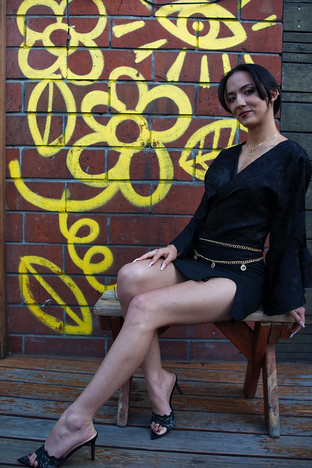 Portrait seated in front of yellow graffiti